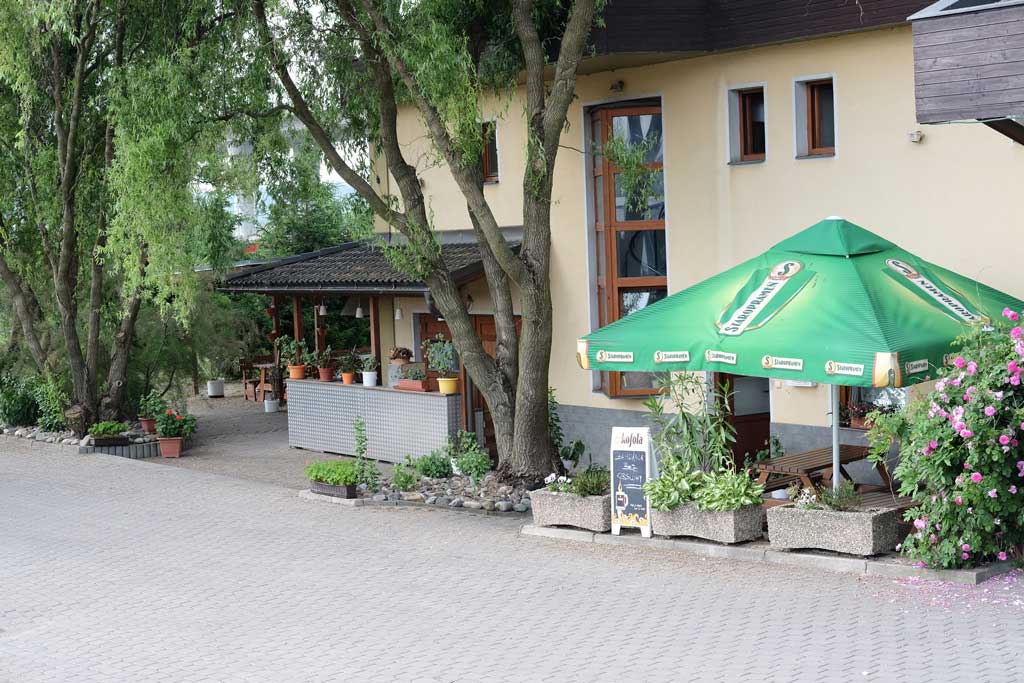 Letní zahrádka motorestu se slunečníkem u stromů