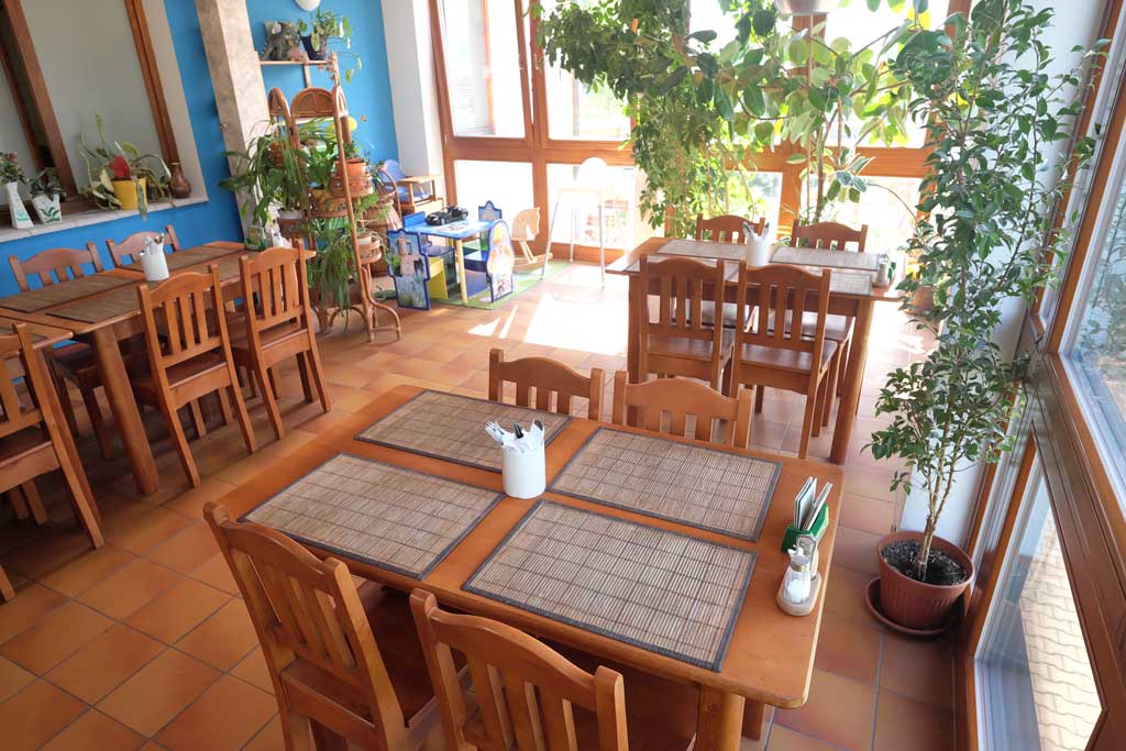 Prosklený sál restaurace plný zeleně s dětským koutkem